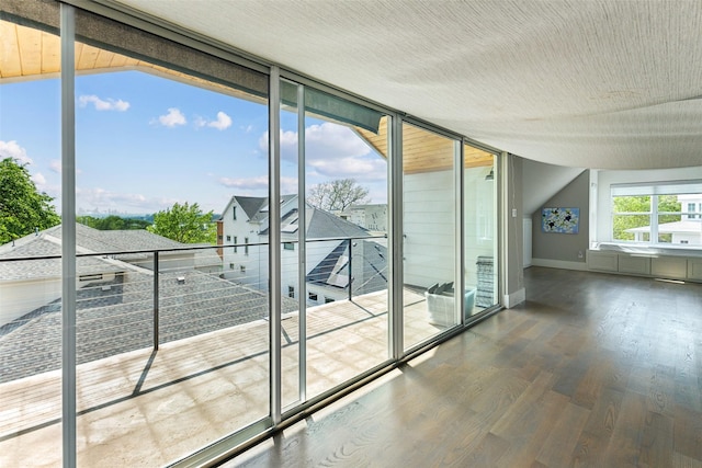 entryway with a wall of windows, wood finished floors, and baseboards