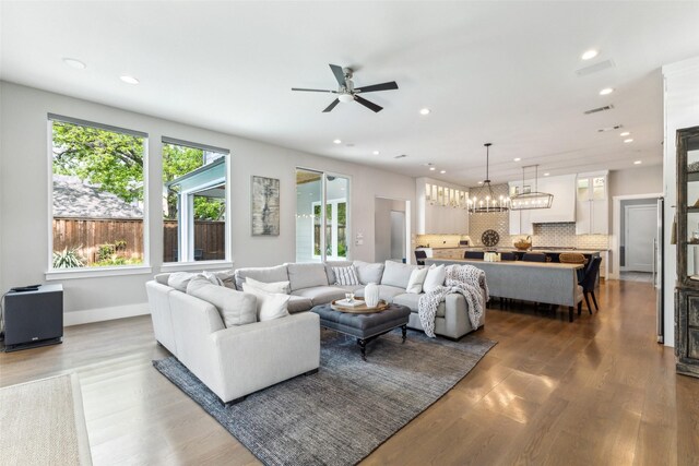 living area with baseboards, recessed lighting, visible vents, ceiling fan with notable chandelier, and wood finished floors