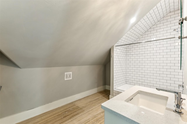 bathroom featuring vaulted ceiling, vanity, wood finished floors, and baseboards