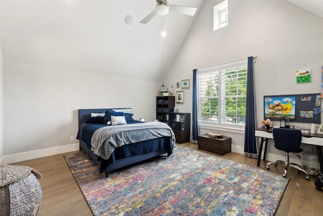 bedroom featuring high vaulted ceiling, wood finished floors, a skylight, ceiling fan, and baseboards