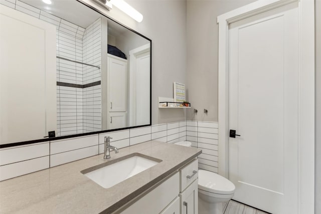 bathroom with tile walls, toilet, and vanity