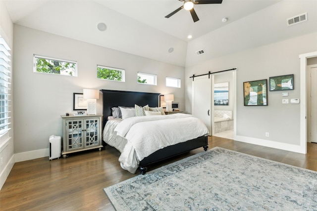 bedroom with a barn door, lofted ceiling, wood finished floors, visible vents, and baseboards