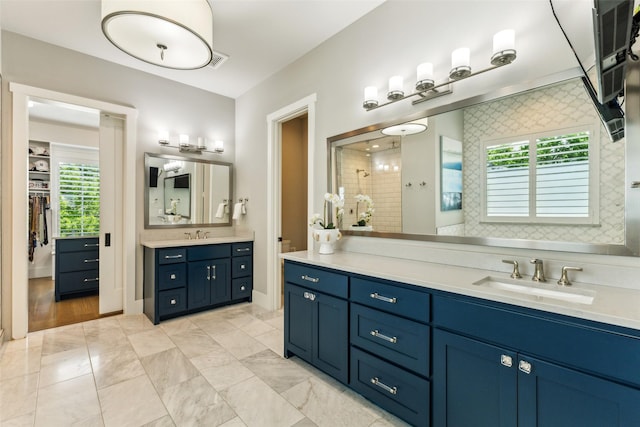 bathroom featuring a walk in closet, vanity, and tiled shower