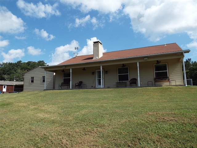 rear view of property with a yard, a patio area, and a chimney