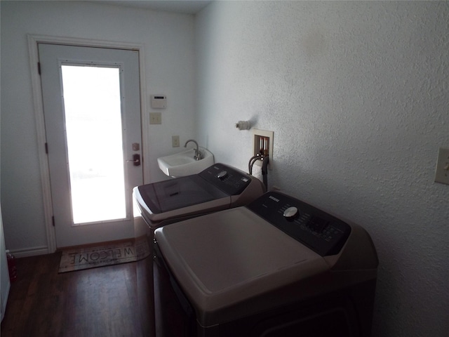 washroom featuring laundry area, wood finished floors, a textured wall, a sink, and washing machine and clothes dryer