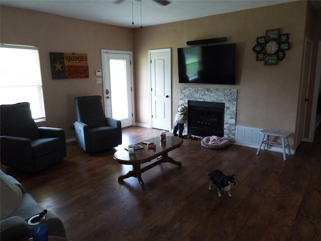 living area with wood finished floors, visible vents, baseboards, a fireplace, and ceiling fan