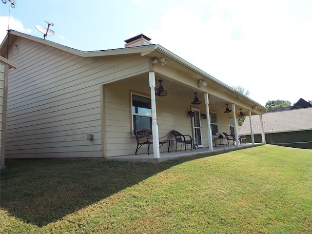 rear view of property with a lawn, a chimney, ceiling fan, and a patio
