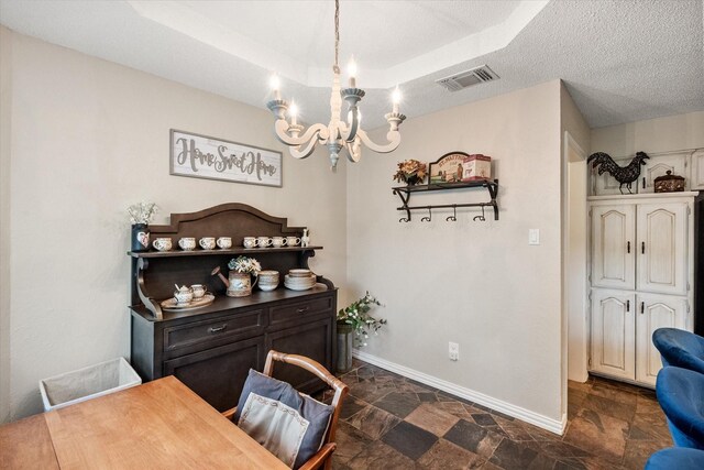 dining space with a textured ceiling, a chandelier, stone finish flooring, baseboards, and visible vents