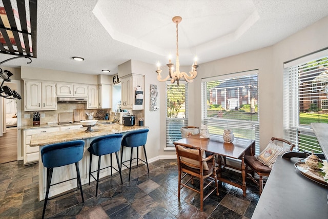 dining space featuring an inviting chandelier, stone tile floors, a textured ceiling, and baseboards