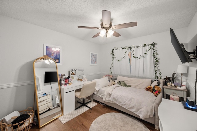 bedroom with wood finished floors, a textured ceiling, and a ceiling fan