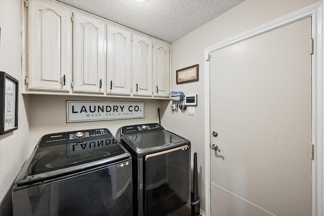 laundry room featuring washing machine and dryer, cabinet space, and a textured ceiling