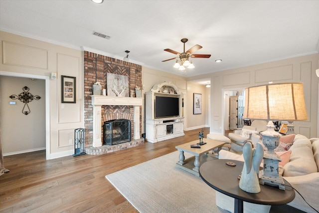 living room featuring ceiling fan, ornamental molding, wood finished floors, and visible vents