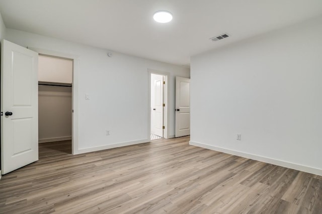 237 Trailridge Dr, Garland, TX 75043 - unfurnished bedroom with baseboards, visible vents, a walk in closet, and light wood finished floors