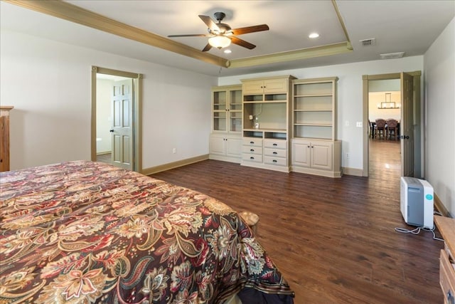 bedroom with a tray ceiling, baseboards, visible vents, and dark wood-style floors