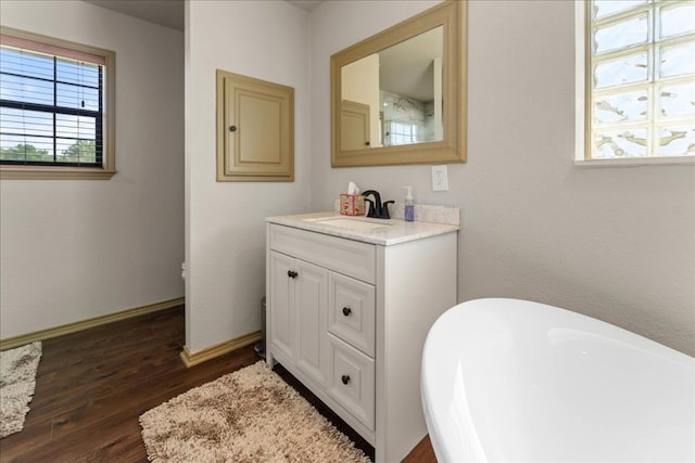 bathroom featuring a freestanding bath, wood finished floors, baseboards, and vanity
