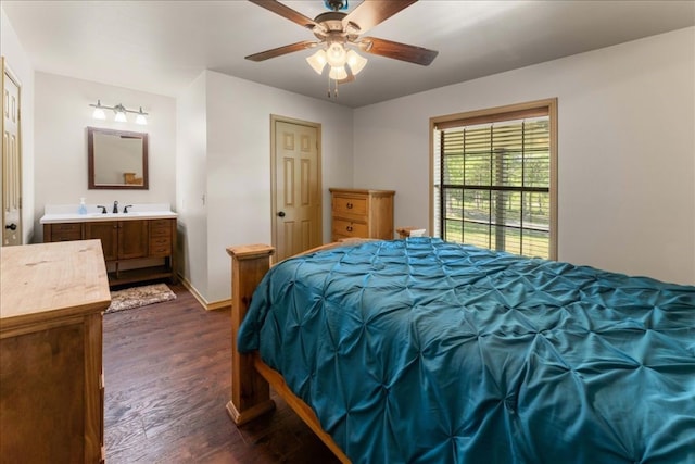 bedroom with dark wood-style floors, a sink, baseboards, a ceiling fan, and connected bathroom