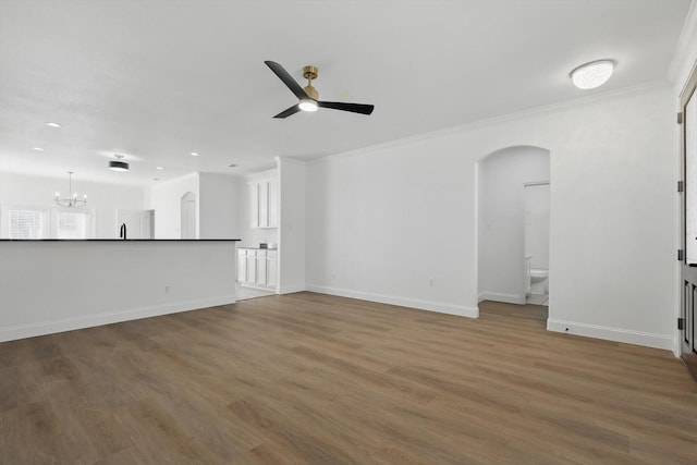 924 Charleston Ln, Savannah, TX 76227 - unfurnished living room with ceiling fan with notable chandelier, wood finished floors, arched walkways, and ornamental molding