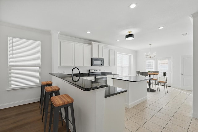 924 Charleston Ln, Savannah, TX 76227 - kitchen with electric stove, black microwave, baseboards, white cabinetry, and a kitchen island