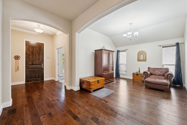 entrance foyer featuring dark wood finished floors, arched walkways, a chandelier, and a wealth of natural light