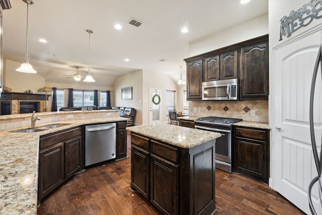 kitchen featuring a stone fireplace, appliances with stainless steel finishes, dark wood-style floors, and a sink