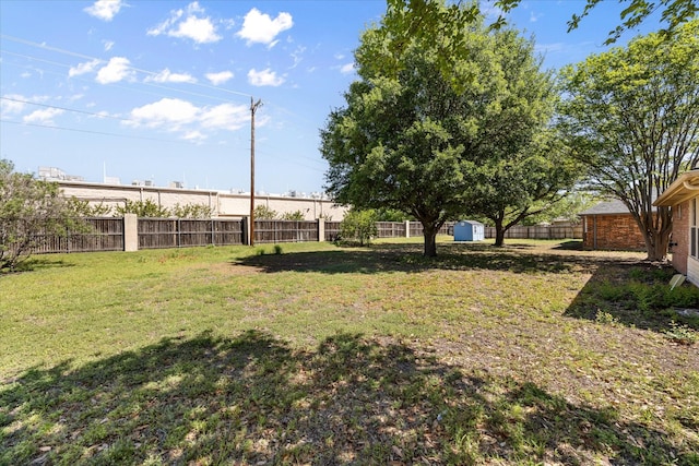 view of yard featuring a fenced backyard, an outdoor structure, and a storage shed