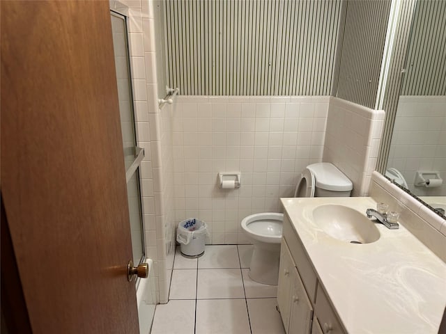 bathroom featuring toilet, vanity, tile patterned floors, and tile walls