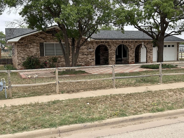 ranch-style home with brick siding, a fenced front yard, and a garage