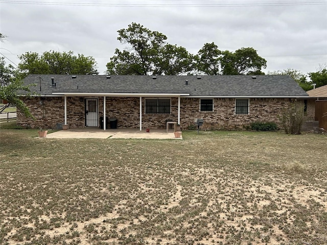back of property with a yard, brick siding, and a patio area