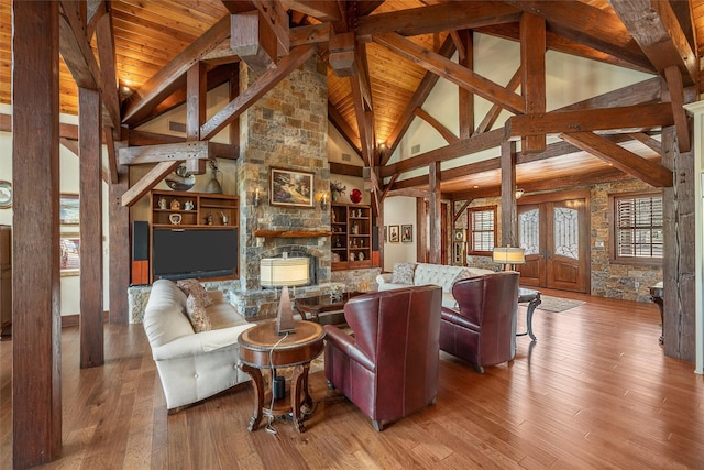 living area featuring high vaulted ceiling, beamed ceiling, wooden ceiling, a fireplace, and wood-type flooring