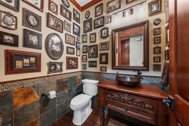 half bathroom with toilet, tile walls, wainscoting, wood finished floors, and vanity