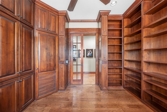 walk in closet with light wood finished floors and a ceiling fan