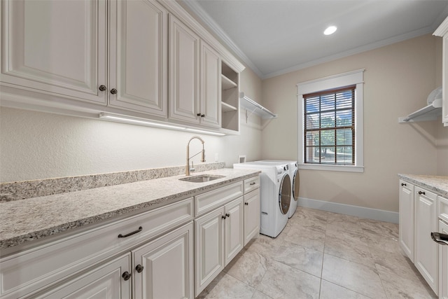 laundry area featuring washing machine and clothes dryer, a sink, baseboards, cabinet space, and ornamental molding