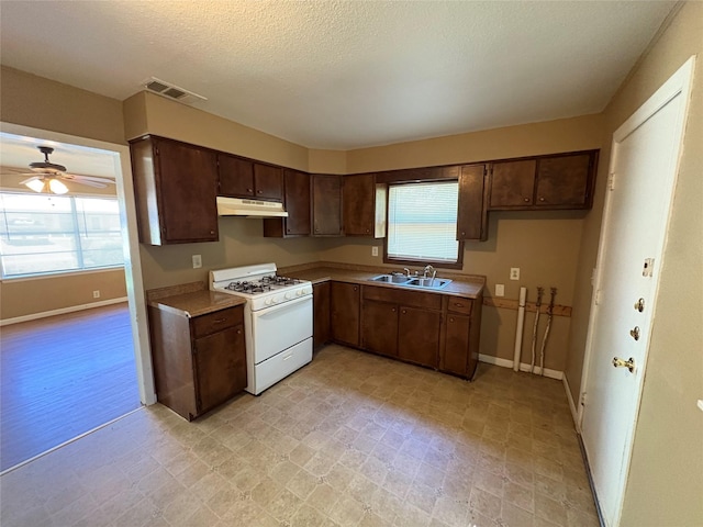 kitchen with visible vents, under cabinet range hood, white range with gas stovetop, and light floors
