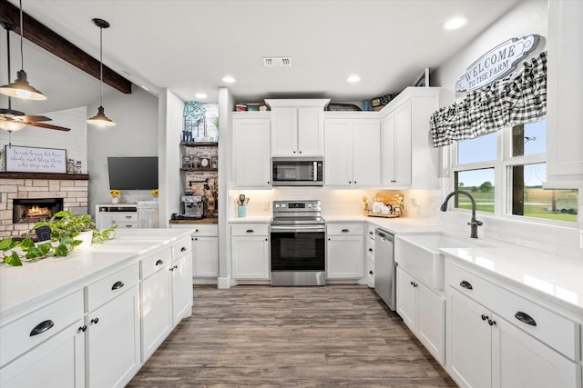 kitchen featuring a sink, light wood-style flooring, stainless steel appliances, white cabinetry, and tasteful backsplash