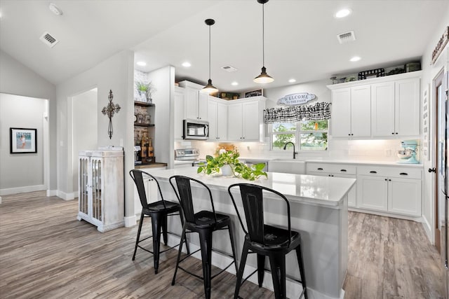 kitchen featuring stainless steel appliances, visible vents, a breakfast bar, and light wood finished floors
