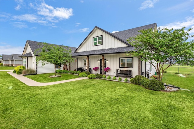 view of front of house with board and batten siding, a shingled roof, a porch, and a front lawn