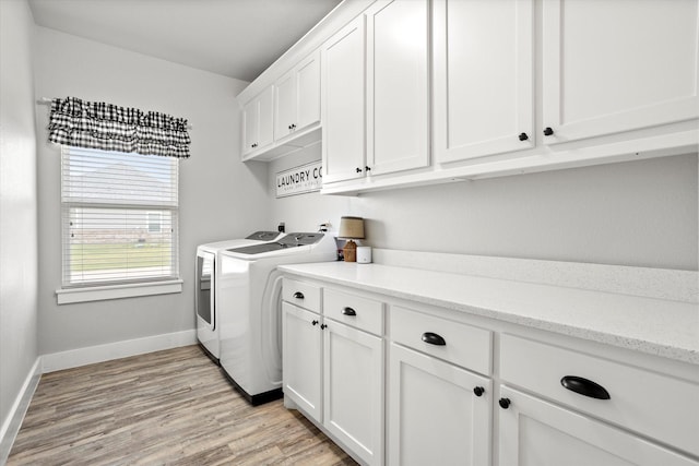 clothes washing area with baseboards, washer and clothes dryer, cabinet space, and light wood finished floors