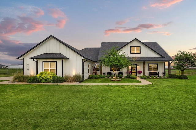 view of front of home with board and batten siding, a shingled roof, and a front yard