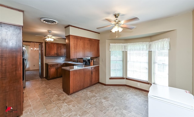 9820 Hillsboro Dr, Shreveport, LA 71118 - kitchen featuring brown cabinets, ceiling fan, a sink, a peninsula, and visible vents