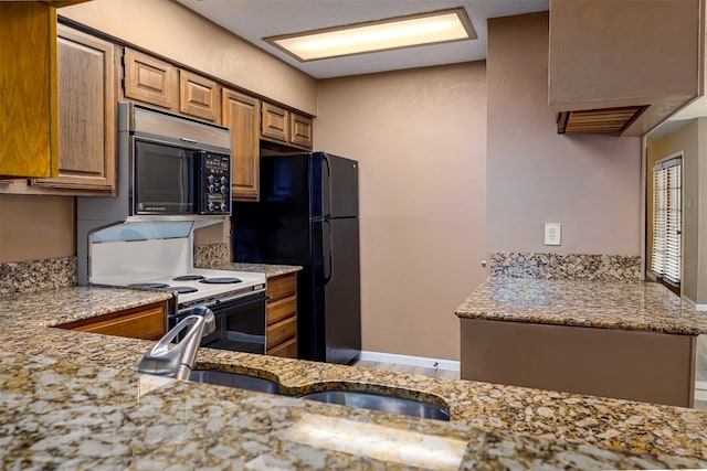 1201 Harwell Dr Unit 225, Arlington, TX 76011 - kitchen featuring range with electric cooktop, light stone countertops, freestanding refrigerator, and brown cabinets