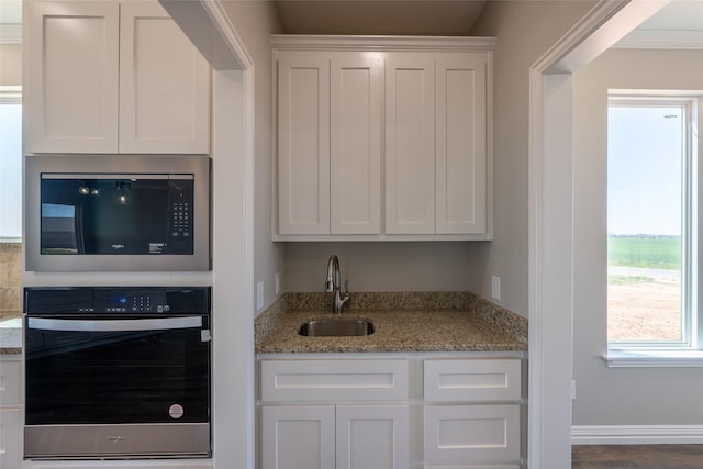 2567 Fm 368, Iowa Park, TX 76367 - kitchen featuring built in microwave, oven, a sink, light stone countertops, and white cabinetry