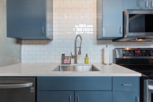 kitchen with tasteful backsplash, light stone countertops, appliances with stainless steel finishes, and a sink