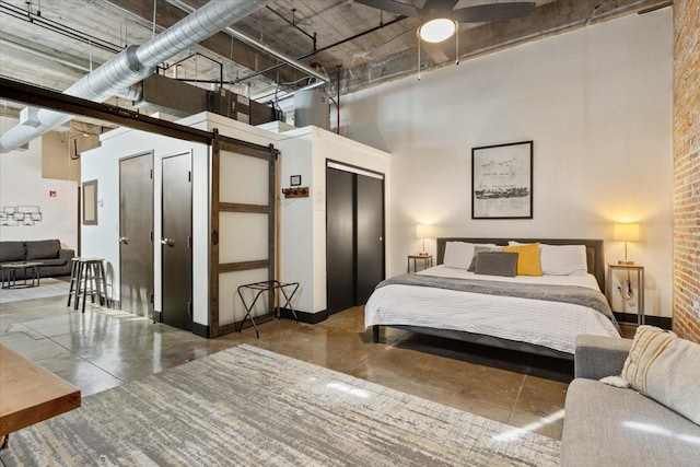 bedroom featuring concrete flooring, a towering ceiling, baseboards, and a barn door