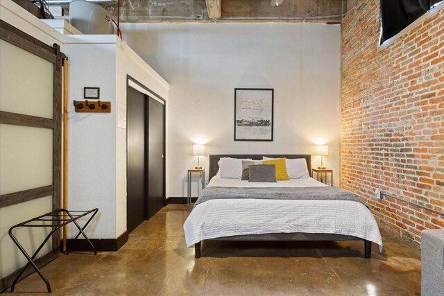 bedroom with a barn door, baseboards, finished concrete floors, and a closet