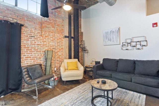living room featuring a high ceiling, a ceiling fan, brick wall, and finished concrete floors