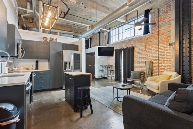 living area featuring concrete floors, a high ceiling, and brick wall