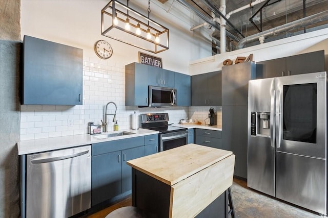 kitchen with wooden counters, appliances with stainless steel finishes, a sink, decorative backsplash, and blue cabinetry