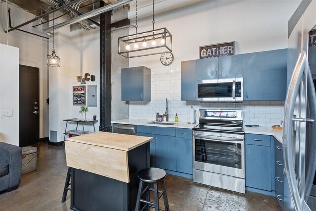 kitchen with stainless steel appliances, a breakfast bar, a sink, and blue cabinetry