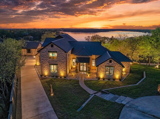 view of front facade with a yard, stone siding, a standing seam roof, and metal roof