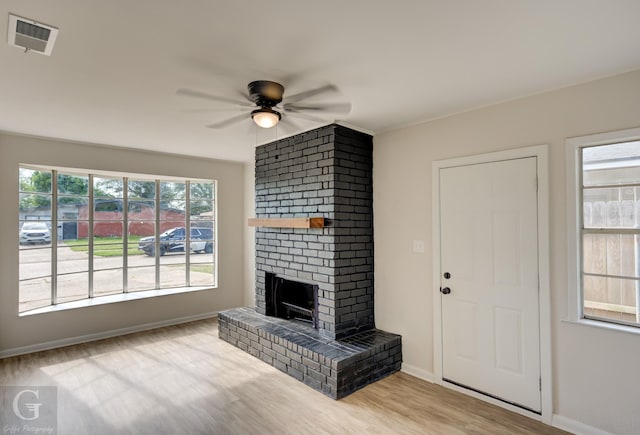 unfurnished living room featuring a ceiling fan, wood finished floors, a fireplace, baseboards, and visible vents